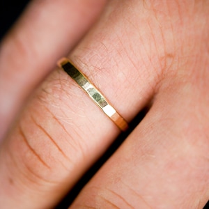 Puede incluir: Primer plano de un anillo de banda de oro en un dedo.