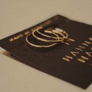 May include: Three gold hammered hoop earrings on a black card with the text "Handmade Jewelry" and "Hanna" in gold lettering.