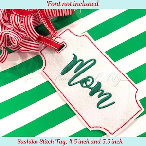 May include: A white felt gift tag with a red border and the word "Mom" embroidered in green script. The tag is attached to a red and white striped ribbon. The tag measures 4.5 inches and 5.5 inches.