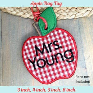 May include: A red and white gingham apple-shaped bag tag with the name "Mrs. Young" embroidered in black. The tag includes a green leaf, a red clasp, and the text "Apple Bag Tag". Available in 3, 4, 5, and 6 inch sizes.