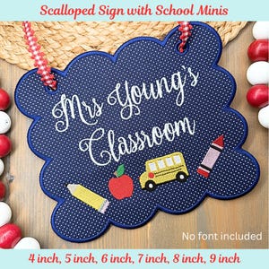 Può includere: Un cartello per l'aula smerlato blu navy con pois bianchi e bordo blu. Il cartello recita "Mrs. Young's Classroom" in corsivo. Presenta immagini ricamate a tema scolastico, tra cui una matita, una mela, un autobus scolastico e un pastello.