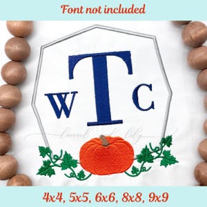 以下が含まれることがあります： 青色のWTCの文字、オレンジ色のカボチャ、緑のつるが特徴の白い刺繍デザイン。 デザインは、銀色の輪郭を持つ白い幾何学的な形状です。 上部のテキストは「Font not included」と書かれています。