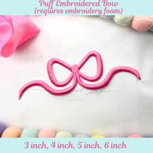 May include: A pink embroidered bow design with the text "Puff Embroidered Bow" and size options of 3, 4, 5, and 6 inches. The design is on a white background with colorful pom-poms.