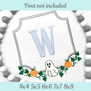 May include: Embroidered design featuring a light blue letter "W" within a gray framed border. The design includes a ghost, pumpkins, and green vines. The text "Font not included" and size options are also present.