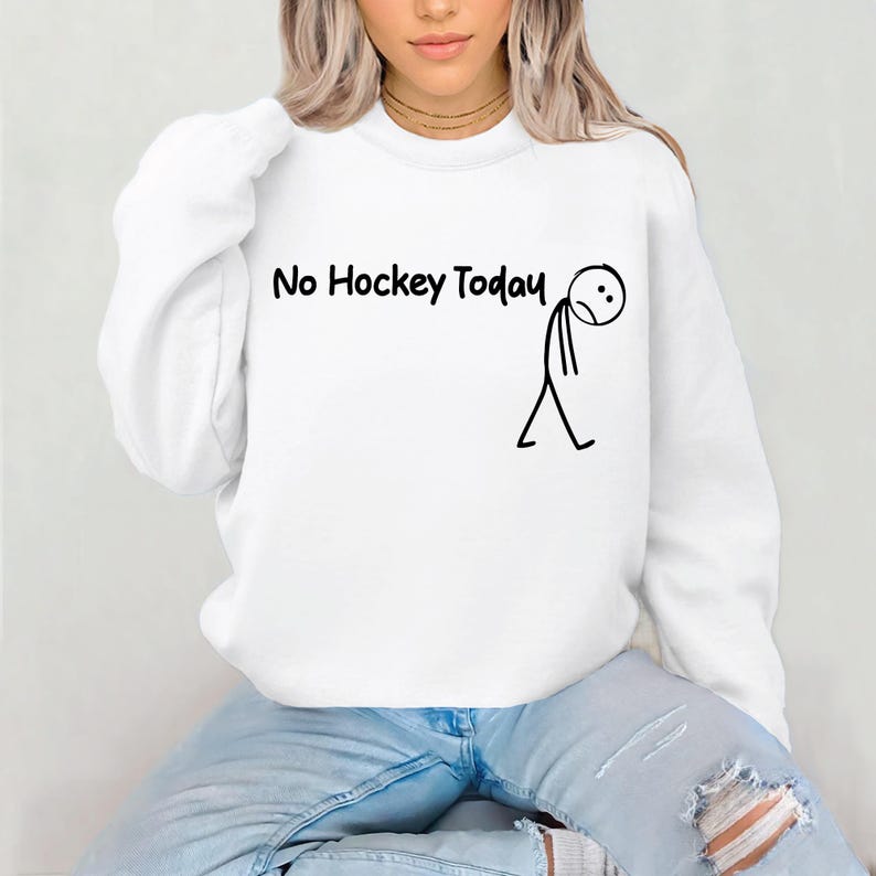 May include: White sweatshirt with the text "No Hockey Today" in black, accompanied by a stick figure with a sad expression. The sweatshirt is a crew neck style.
