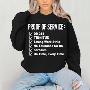 Puede incluir: Sudadera negra con la frase "PROOF OF SERVICE:" y una lista de verificación que incluye "DD-214", "TINNITUS", "Sarcasm" y "On Time, Every Time" en blanco.