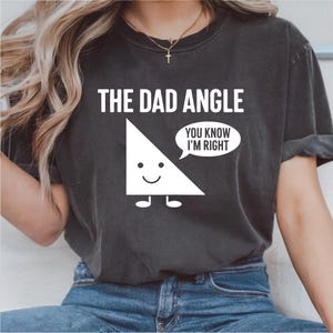 May include: Dark gray t-shirt with the text "THE DAD ANGLE" and a cartoon triangle character. The triangle has a smiling face and the speech bubble says "YOU KNOW I'M RIGHT".