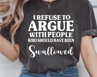 Könnte beinhalten: Dunkelgraues T-Shirt mit dem weißen Text "I REFUSE TO ARGUE WITH PEOPLE WHO SHOULD HAVE BEEN Swallowed." Das Shirt hat kurze Ärmel und einen Rundhalsausschnitt. Das Model trägt blaue Jeans.