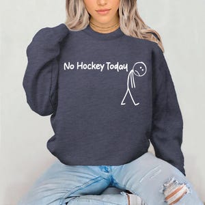 May include: Navy blue sweatshirt with the text "No Hockey Today" and a stick figure with a sad face. The sweatshirt is a crew neck style and is made of a soft material.
