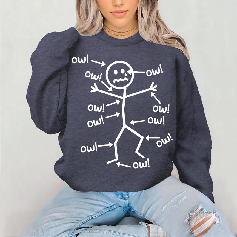 Puede incluir: Sudadera azul marino con un dise&ntilde;o de figura de palo blanca. La figura tiene flechas que apuntan a diferentes partes del cuerpo, cada una con la palabra "ow!". Un dise&ntilde;o humor&iacute;stico y casual.