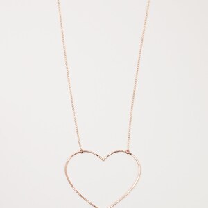 May include: A delicate rose gold necklace featuring a large heart pendant. The heart is formed by a single wire, creating an open, minimalist design. The chain and clasp are also rose gold, creating a cohesive look.