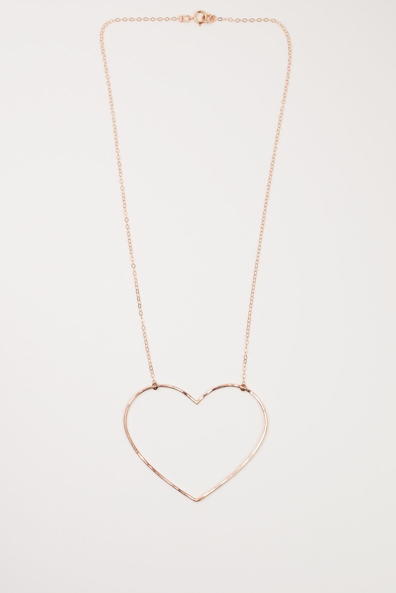 May include: A delicate rose gold necklace featuring a large heart pendant. The heart is formed by a single wire, creating an open, minimalist design. The chain and clasp are also rose gold, creating a cohesive look.
