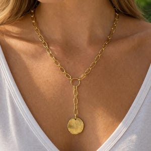 May include: A white ceramic mug with a black handle and the text "But First, Coffee" in a bold, black font. The mug is set against a blurred background, suggesting a cosy setting.