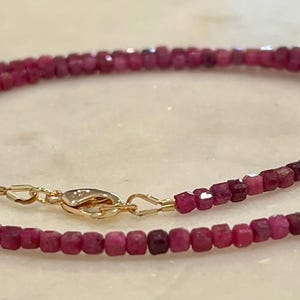 Puede incluir: Un delicado collar con peque&ntilde;as cuentas de rub&iacute; facetadas en un tono rosa intenso. El collar est&aacute; ensartado con un cierre dorado. Las cuentas son de tama&ntilde;o uniforme y crean una hebra continua y elegante.