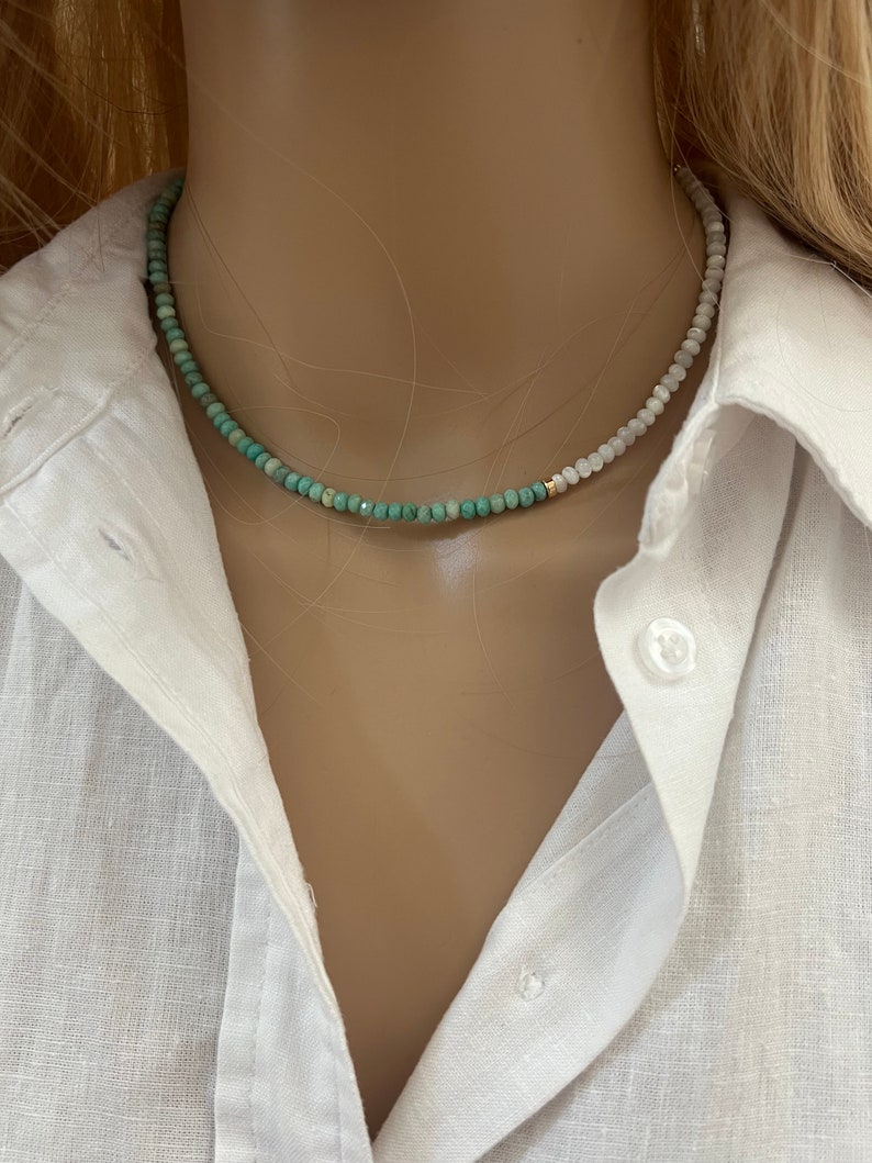 May include: A delicate, two-toned necklace with green and white beads. The necklace is made of small, round beads and is strung on a gold chain.