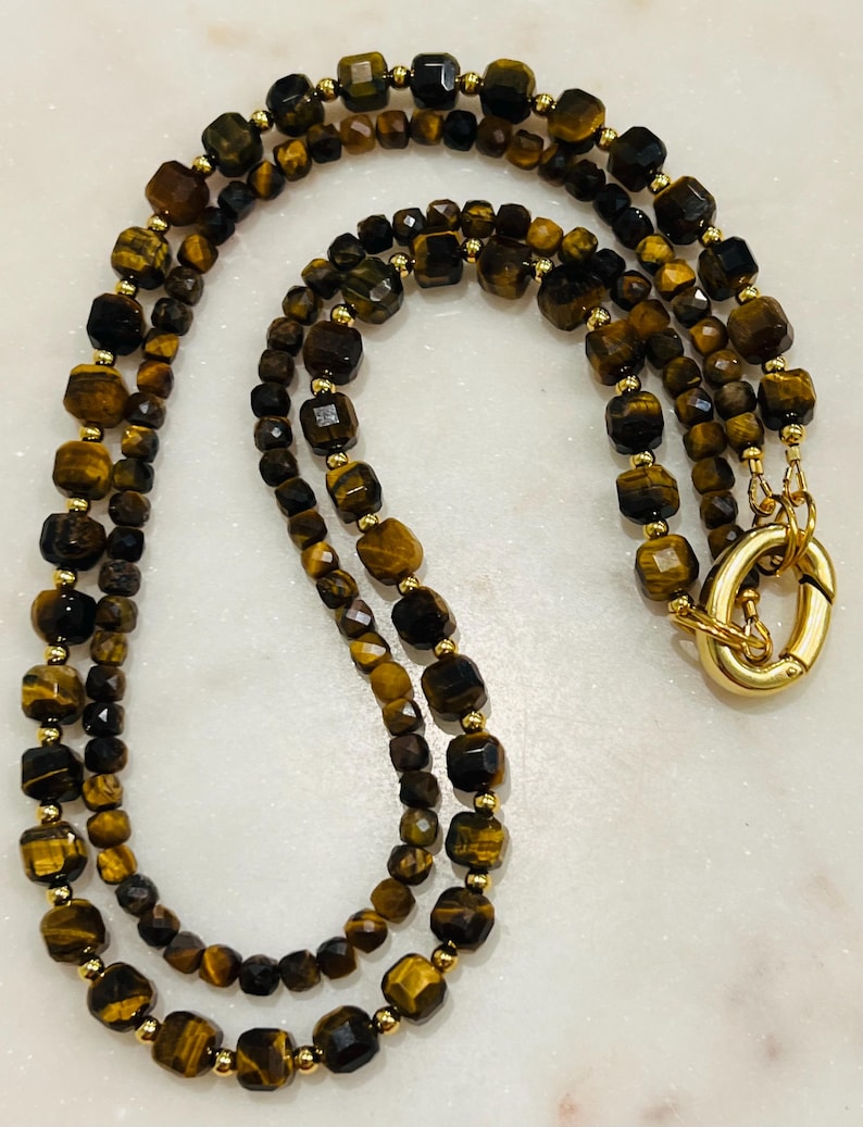 May include: A double-strand necklace made with tiger's eye beads. The beads are faceted and have a gold-toned metal clasp.