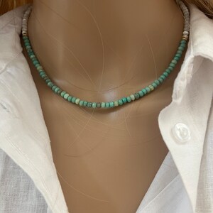 May include: A turquoise and white beaded necklace on a mannequin. The necklace is made of small, round beads.
