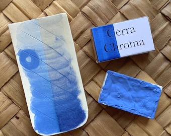 Può includere: Un panno di acquerello blu con il testo "Cerra Chroma" sulla confezione. Il panno è su un tappetino intrecciato.