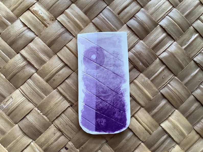 Pu&ograve; includere: Una carta campione di inchiostro viola con un motivo diagonale. L'inchiostro &egrave; di colore viola intenso e ha una leggera lucentezza.