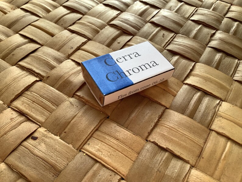 May include: A small white box with blue accents. The box has the text "Cerra Chroma" and "Fire from cone 06-10" printed on it.