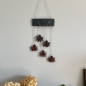 May include: A ceramic wall hanging with a blue and green patterned base and five brown ceramic spiders hanging from it.
