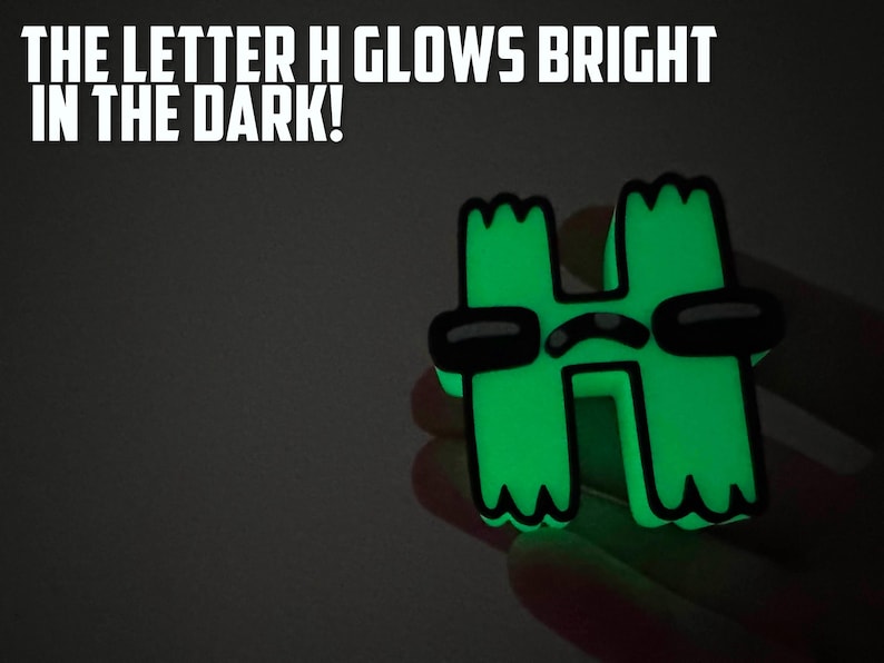 May include: A green glow-in-the-dark letter H with a cartoon face and sunglasses. The letter H glows brightly in the dark. The text "THE LETTER H GLOWS BRIGHT IN THE DARK!" is above the letter.