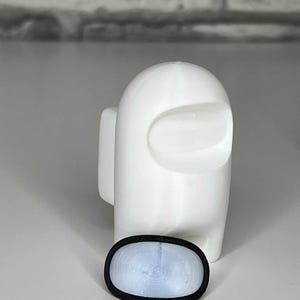 K&ouml;nnte beinhalten: Wei&szlig;e 3D-gedruckte Figur eines Charakters aus dem Videospiel Among Us. Die Figur steht auf einer wei&szlig;en Oberfl&auml;che. Ein schwarz-wei&szlig;es Visier befindet sich vor der Figur.