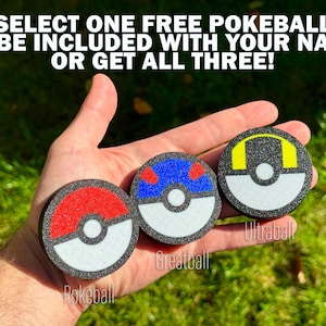 May include: Three circular Pokeball designs are shown, featuring red and white, blue and white, and yellow and black colour schemes. The text reads, "SELECT ONE FREE POKEBALL TO BE INCLUDED WITH YOUR NAME OR GET ALL THREE!" The Pokeballs are held in a hand.