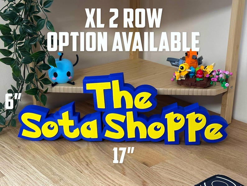 May include: A blue and yellow sign reading "The Sota Shoppe" is 43 cm long and 15 cm tall. The text "XL 2 ROW OPTION AVAILABLE" is above the sign. Small toys are on the shelf behind the sign.
