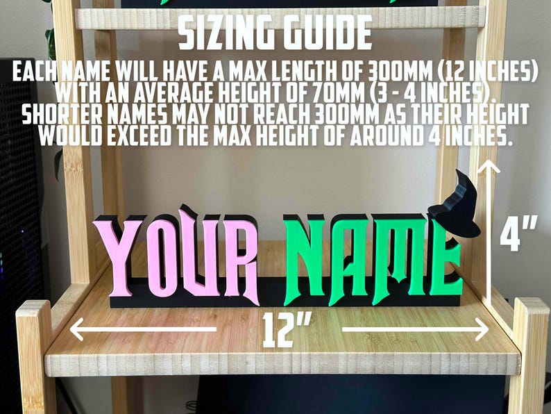 May include: A black sign with the words "YOUR NAME" in pink and green letters. The sign is 12 inches long and 4 inches tall. The sign is on a wooden shelf.