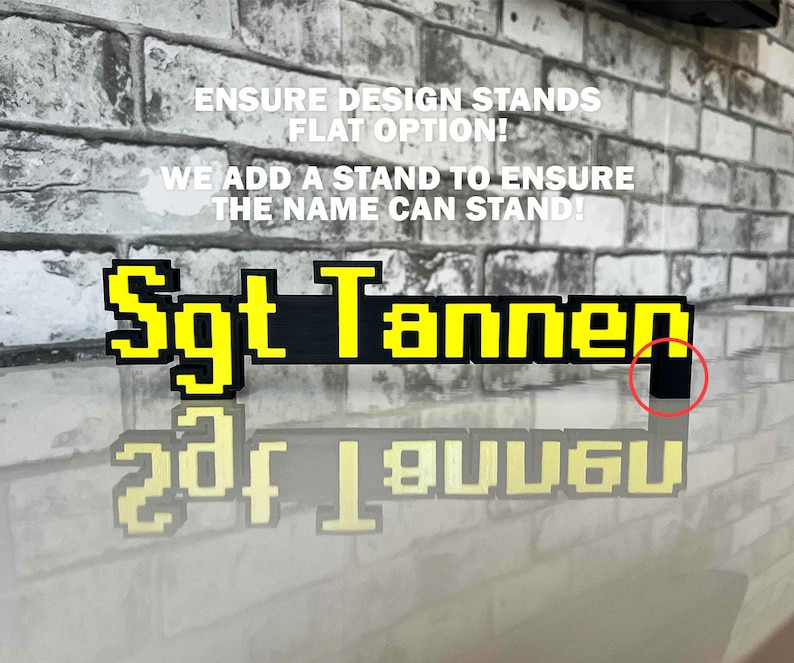 May include: A black and yellow pixelated name sign that reads "Sgt Tannen". The sign is made to stand up on a small black stand.