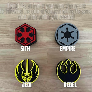 Peut inclure: Quatre logos Star Wars diff&eacute;rents, chacun avec un sch&eacute;ma de couleurs diff&eacute;rent. Les logos sont pour les factions Sith, Empire, Jedi et Rebel. Les logos sont imprim&eacute;s sur une surface en bois.