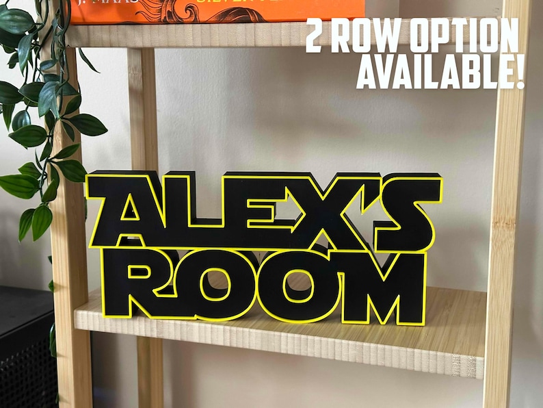 Peut inclure: Une enseigne en bois noire et jaune avec l'inscription "ALEX'S ROOM" sur une &eacute;tag&egrave;re en bois. L'enseigne est en deux rang&eacute;es avec "ALEX'S" sur la rang&eacute;e du haut et "ROOM" sur la rang&eacute;e du bas. Le texte "2 ROW OPTION AVAILABLE!" est &eacute;crit en blanc sur fond noir au-dessus de l'enseigne.