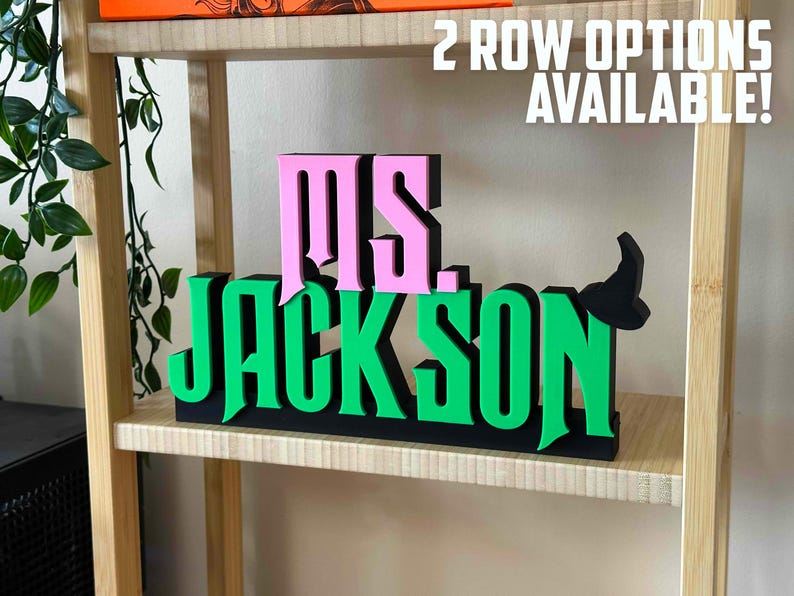 May include: A wooden sign with the words "MS. JACKSON" in pink and green letters. The sign is on a shelf with the text "2 ROW OPTIONS AVAILABLE!" above it.