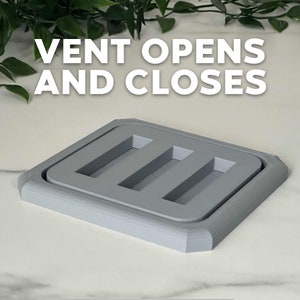 Puede incluir: Una rejilla de ventilaci&oacute;n de pl&aacute;stico gris con tres aberturas rectangulares. La rejilla de ventilaci&oacute;n est&aacute; dise&ntilde;ada para abrirse y cerrarse, como indica el texto "VENT OPENS AND CLOSES".