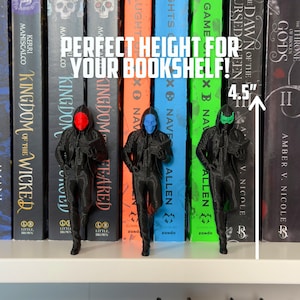 May include: Three black figurines with colored masks (red, blue, and green) stand in front of a row of books. The figurines are approximately 4.5 inches tall. The text "PERFECT HEIGHT FOR YOUR BOOKSHELF!" is displayed above the figurines.