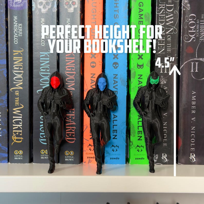 May include: Three black figurines with colored masks (red, blue, and green) stand in front of a row of books. The figurines are approximately 4.5 inches tall. The text "PERFECT HEIGHT FOR YOUR BOOKSHELF!" is displayed above the figurines.
