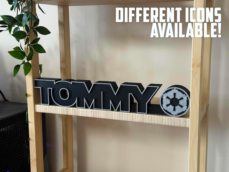 Peut inclure: Une enseigne en bois noir avec le mot "TOMMY" en lettres blanches. L'enseigne est sur une &eacute;tag&egrave;re en bois avec un petit symbole gris de Star Wars &agrave; droite de l'enseigne. Le texte "DIFFERENTS ICONS DISPONIBLES !" est &eacute;crit en lettres blanches sur fond noir au-dessus de l'enseigne.