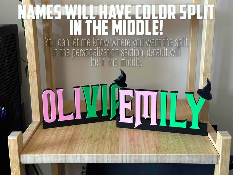 May include: Two names, "Olivia" and "Emily", are displayed in a split color design. The names are in pink and green, with a black background. The names are separated by a small witch's hat.
