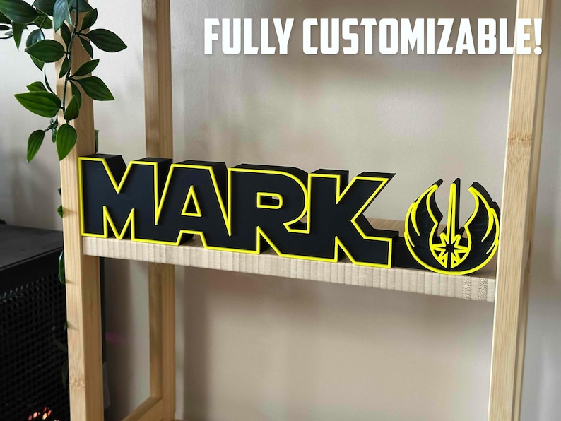 Peut inclure: Une enseigne en bois noire avec une bordure jaune orthographiant "MARK" avec un symbole Star Wars jaune et noir &agrave; droite. L'enseigne est sur une &eacute;tag&egrave;re en bois.