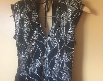 May include: A black sleeveless dress with a V-neck and a silver sequined pattern.
