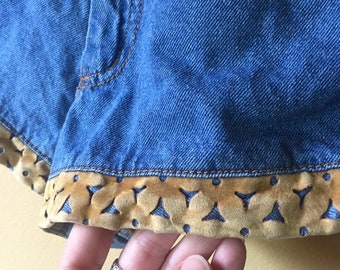 May include: Blue denim shorts with a brown velvet trim featuring a cut-out design.