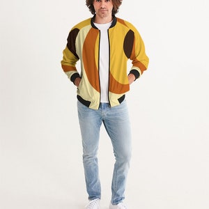 May include: A yellow, brown, and black bomber jacket with a geometric pattern. The jacket has a zipper closure and ribbed cuffs and waistband.