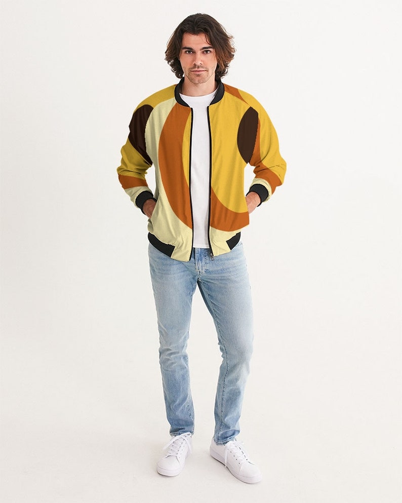 May include: A yellow, brown, and black bomber jacket with a geometric pattern. The jacket has a zipper closure and ribbed cuffs and waistband.