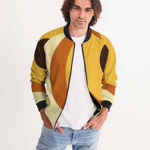 May include: A yellow, orange, and brown bomber jacket with a geometric pattern. The jacket has a black zipper and black ribbed cuffs and collar.