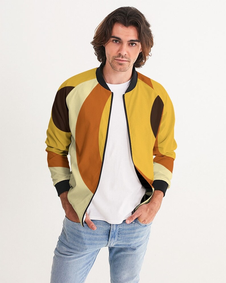 May include: A yellow, orange, and brown bomber jacket with a geometric pattern. The jacket has a black zipper and black ribbed cuffs and collar.
