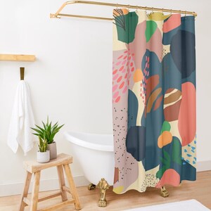 May include: A colorful shower curtain with an abstract design. The curtain features large shapes in shades of blue, pink, orange, and green against a cream background. The curtain hangs from a gold-colored rod in a bathroom setting.