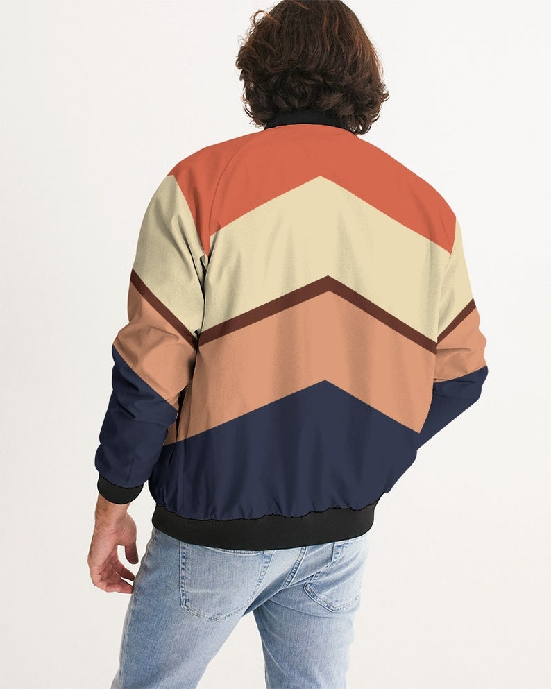 Op de afbeelding: Een bomberjack met een geometrisch patroon in tinten oranje, bruin, beige en donkerblauw.