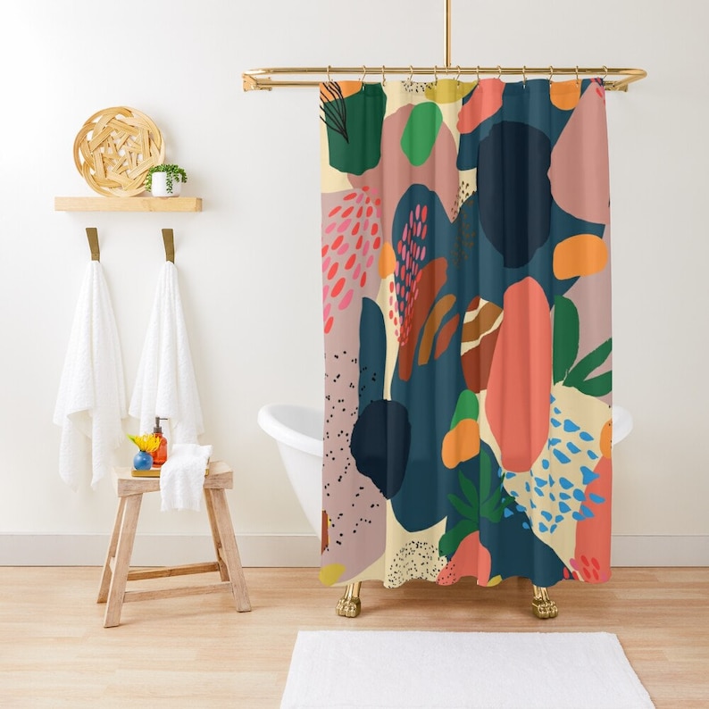 May include: A colorful shower curtain with an abstract design. The pattern features large, overlapping shapes in shades of navy, coral, pink, green, and orange on a cream background. The curtain hangs in a bathroom setting.