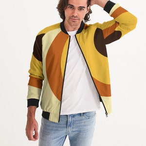 May include: A yellow, orange, and brown bomber jacket with a geometric pattern. The jacket has a black zipper and black ribbed cuffs and waistband.